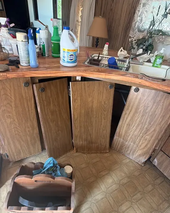 Countertop crowded with bottles and products, cabinets left open