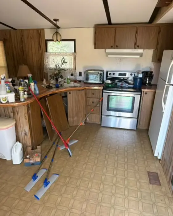 Messy kitchen with brooms and mops on the floor