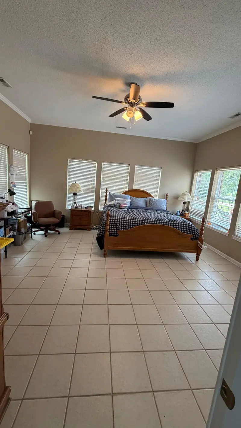 Spacious bedroom with a made bed and clean tile floor